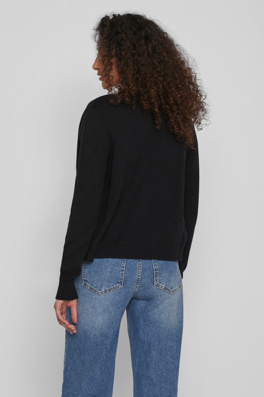 Gilet noir de VILA® porté avec un jean bleu, vue de dos, manches longues.