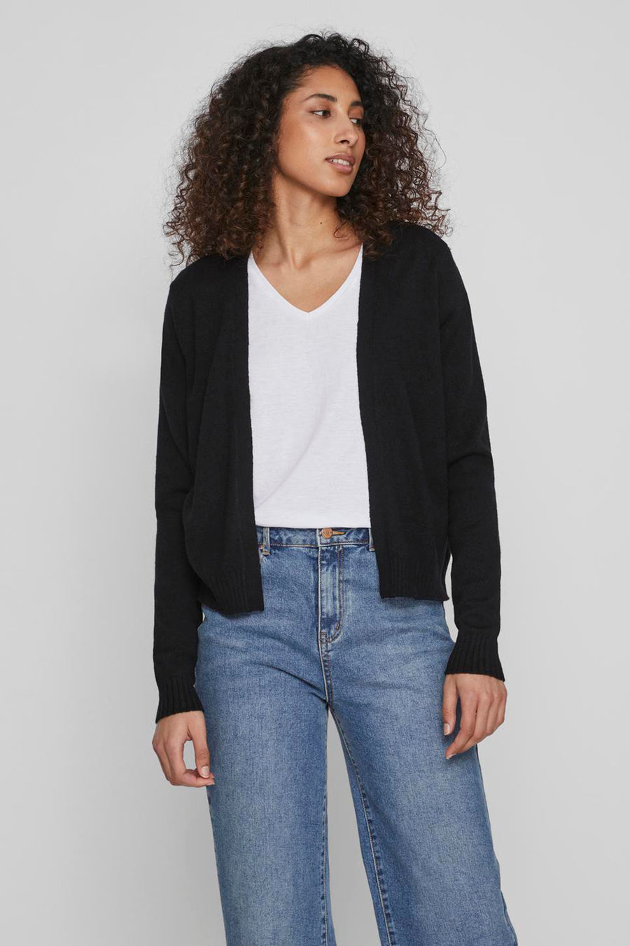 Gilet noir de VILA, porté sur un t-shirt blanc avec un jean bleu taille haute.