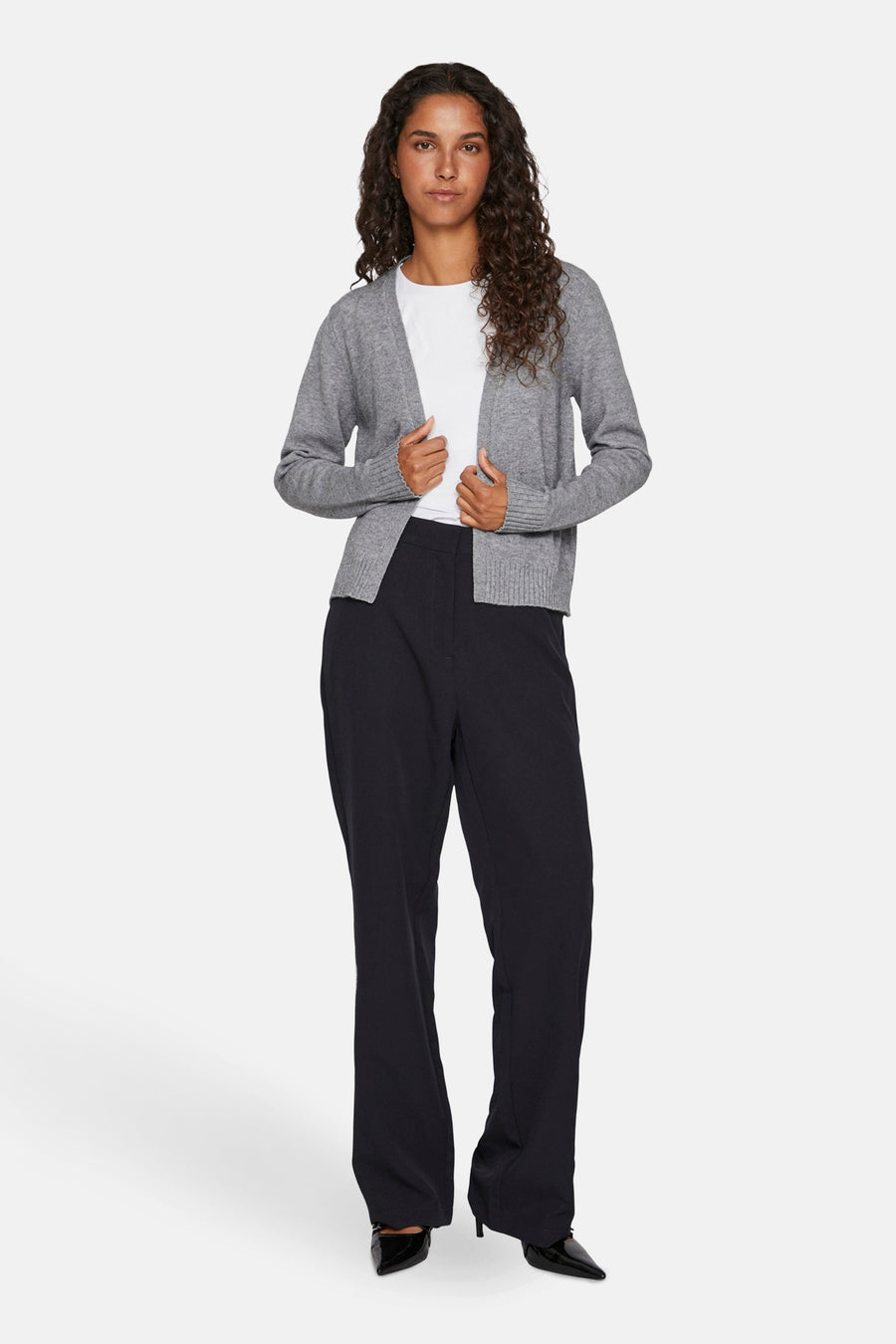 Cardigan gris de VILA®, porté sur un t-shirt blanc et un pantalon noir ample avec des escarpins.