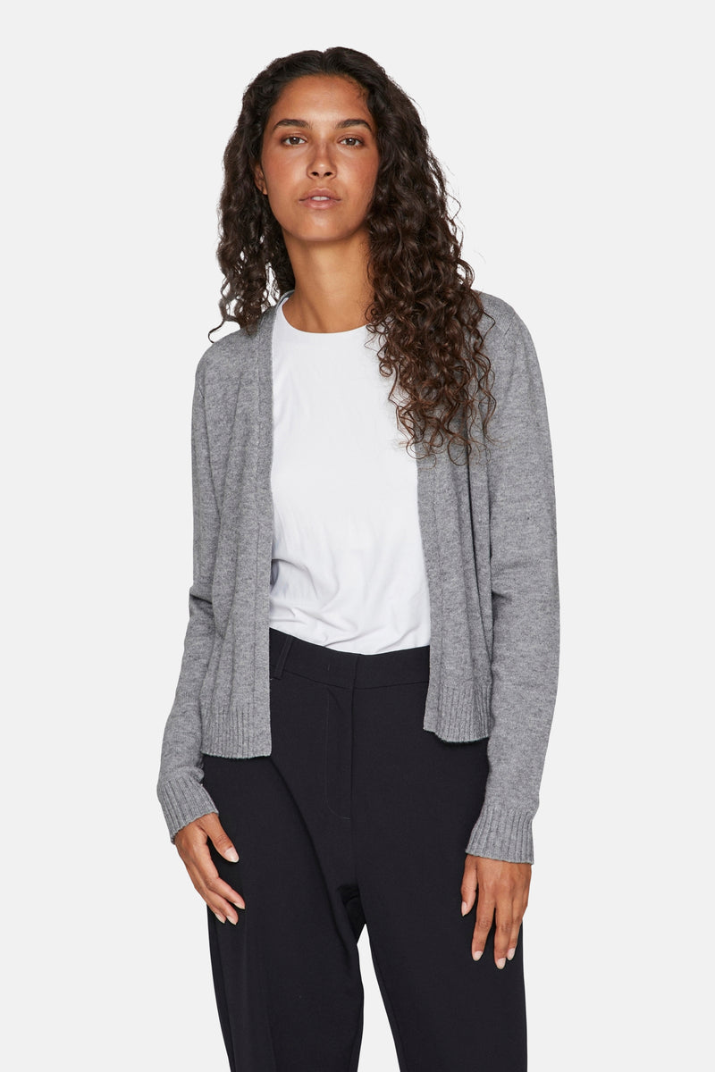 Grijze gebreide cardigan van VILA®, gedragen over een wit T-shirt en een zwarte broek.