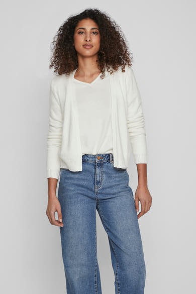 Cardigan blanc de VILA, porté sur un t-shirt blanc à col en V et un jean bleu délavé.