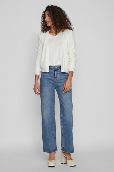 Cardigan blanc de VILA, porté sur un T-shirt blanc et un jean bleu ample.