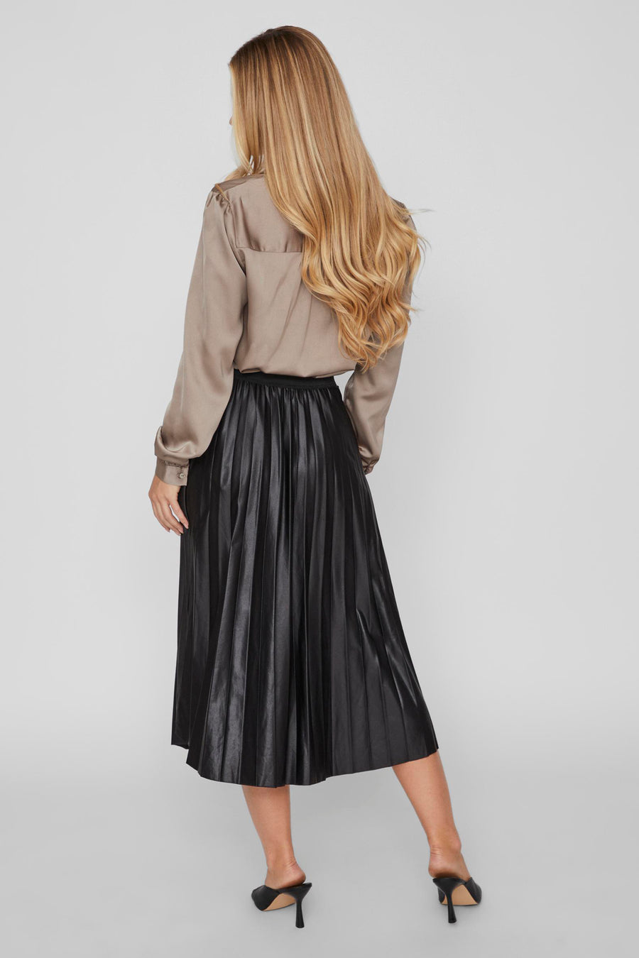 Zwarte midi-rok van VILA, geplooid en glanzend, gedragen met een satijnen blouse en hakken.