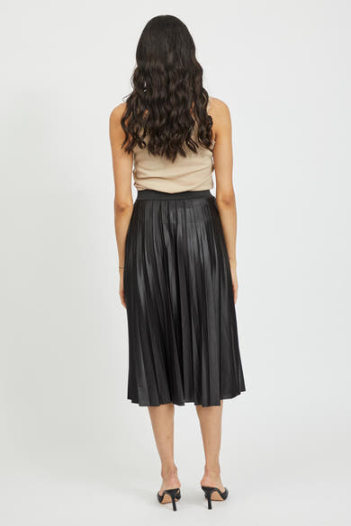 Zwarte geplooide midi-rok van VILA®, gedragen met een beige tanktop en zwarte stiletto muiltjes.