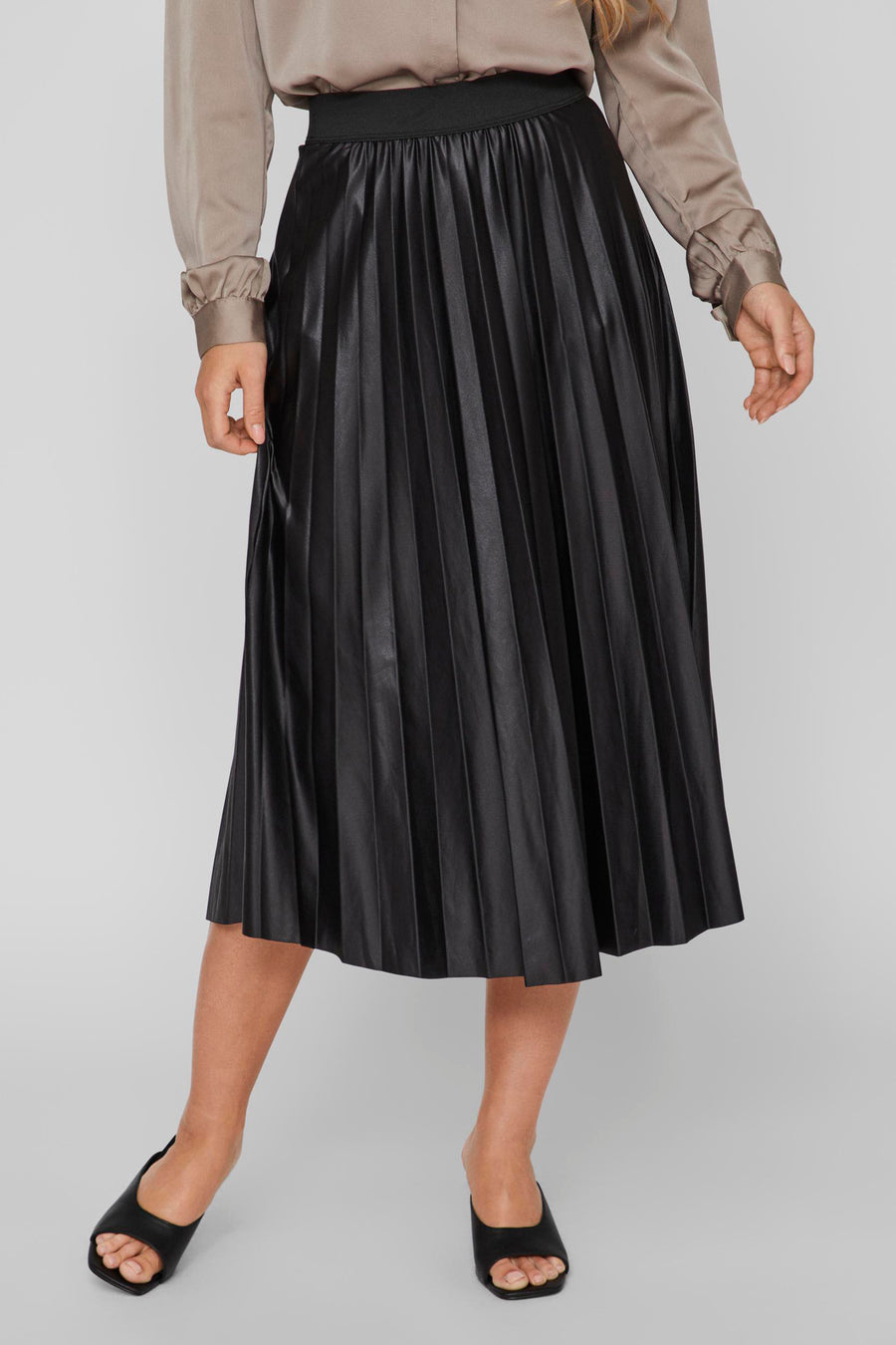 Zwarte geplooide midi-rok van VILA®, gedragen met een beige blouse en zwarte muiltjes met hak.
