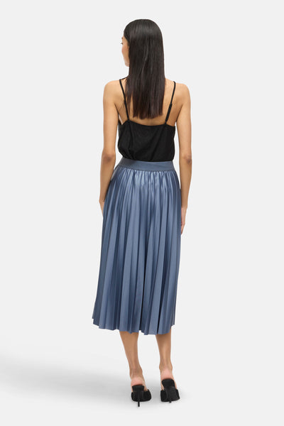 Jupe 3/4 bleue van VILA®, plissée et mi-longue, portée avec un débardeur noir et des mules.