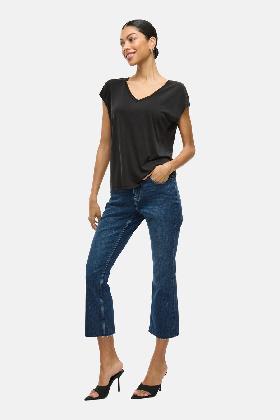 Top uni noir de VILA®, porté avec un jean bleu et des talons hauts noirs.
