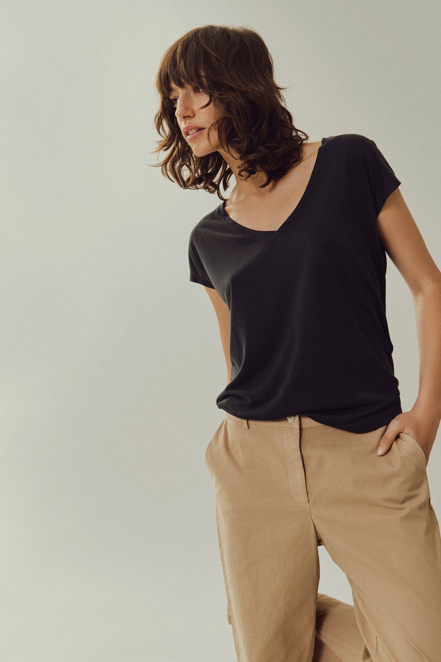 Top noir uni manche courte de VILA, porté avec un pantalon beige en coton.