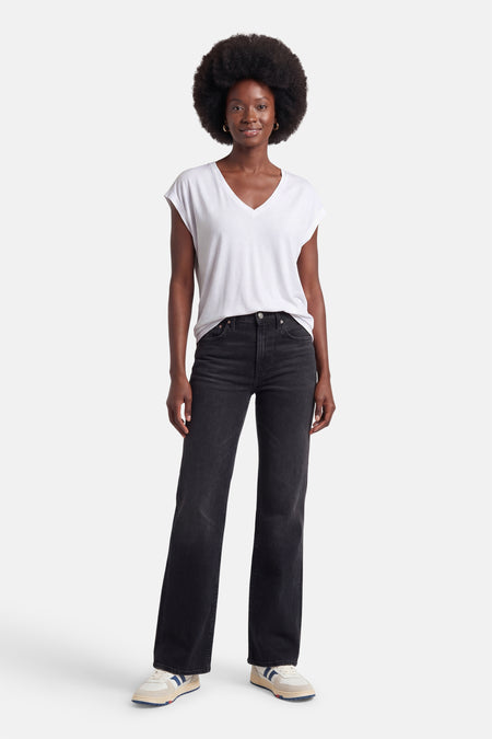 T-shirt blanc uni à manches courtes de VILA® à col en V, porté par une femme avec un jean et des baskets.
