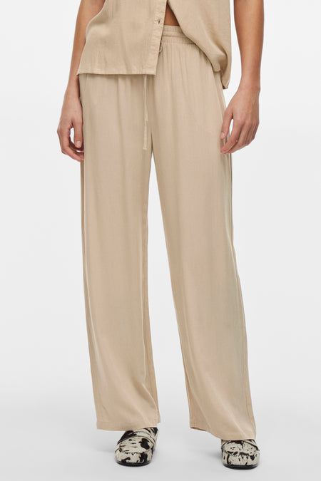Beige broek van VILA, met trekkoord en wijde pasvorm, gedragen met een schoen met patroon.