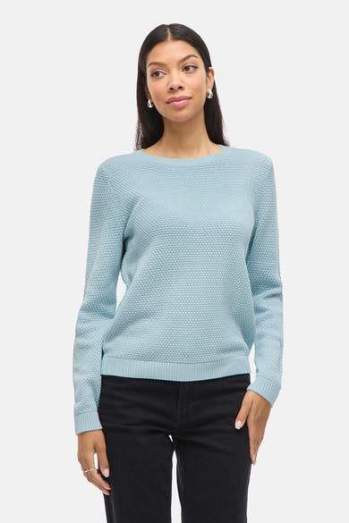 Blauwe trui met ronde hals van VILA, gedragen met een zwarte broek met hoge taille en leren enkellaarsjes.