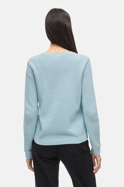 Pull à col rond bleu de VILA, avec une texture gaufrée, porté avec un jean noir.