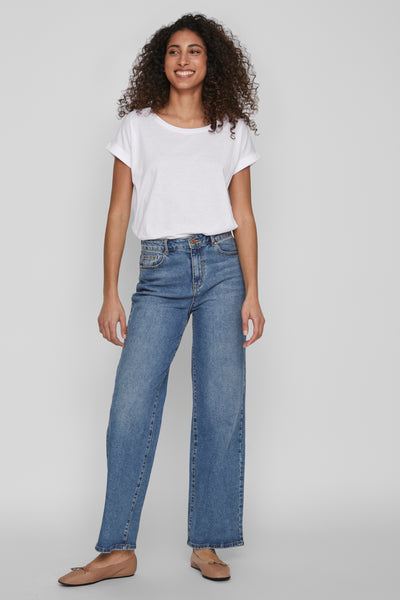 Top blanc uni à manches courtes de VILA, porté avec un jean bleu taille haute et des ballerines marron.

