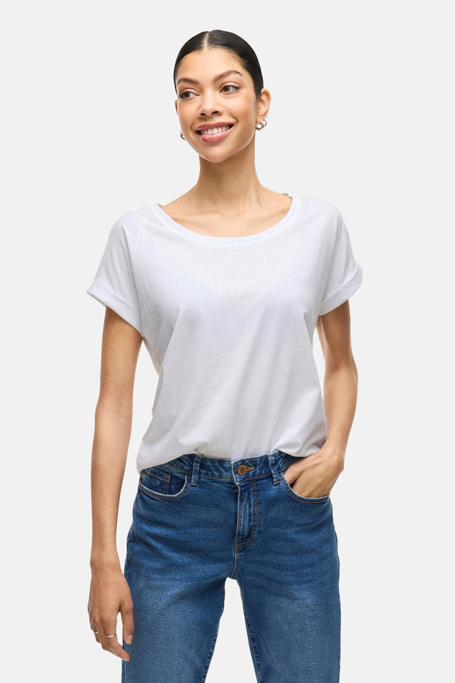 Wit topje van VILA, gedragen met een high-waisted blauwe jeans en zilveren oorbellen.