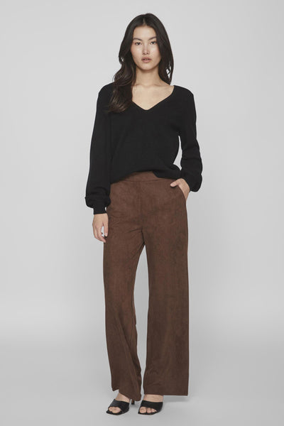 Pull col V noir de VILA®, porté avec un pantalon marron large et des sandales noires.