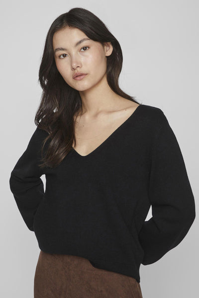 Pull noir col V de VILA®, porté avec un pantalon marron, manches longues.
