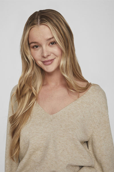 Pull beige col V de VILA, en tricot fin, porté par une femme souriante.
