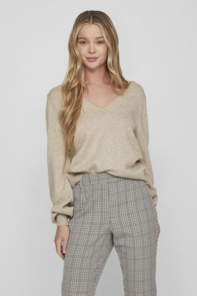 Pull col V beige de VILA, avec des manches longues et un pantalon à carreaux.
