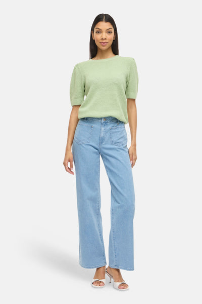 Pull vert de VILA, à manches courtes bouffantes, porté avec un jean taille haute et des mules blanches.