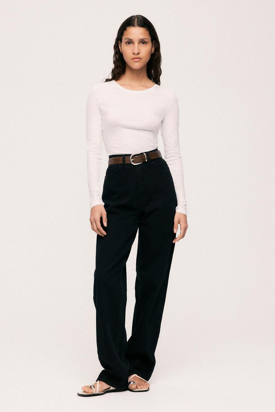 Rechte zwarte denim jeans van VILA®, hoge taille, gedragen met een witte top, een bruine riem en sandalen.
