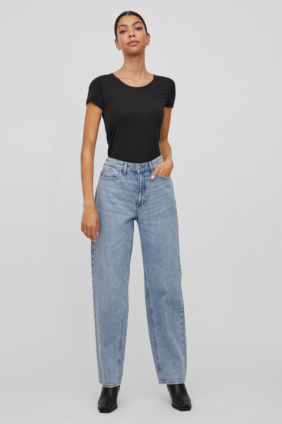 Wijde blauwe jeans van VILA, gedragen met een zwart T-shirt en zwarte enkellaarsjes.