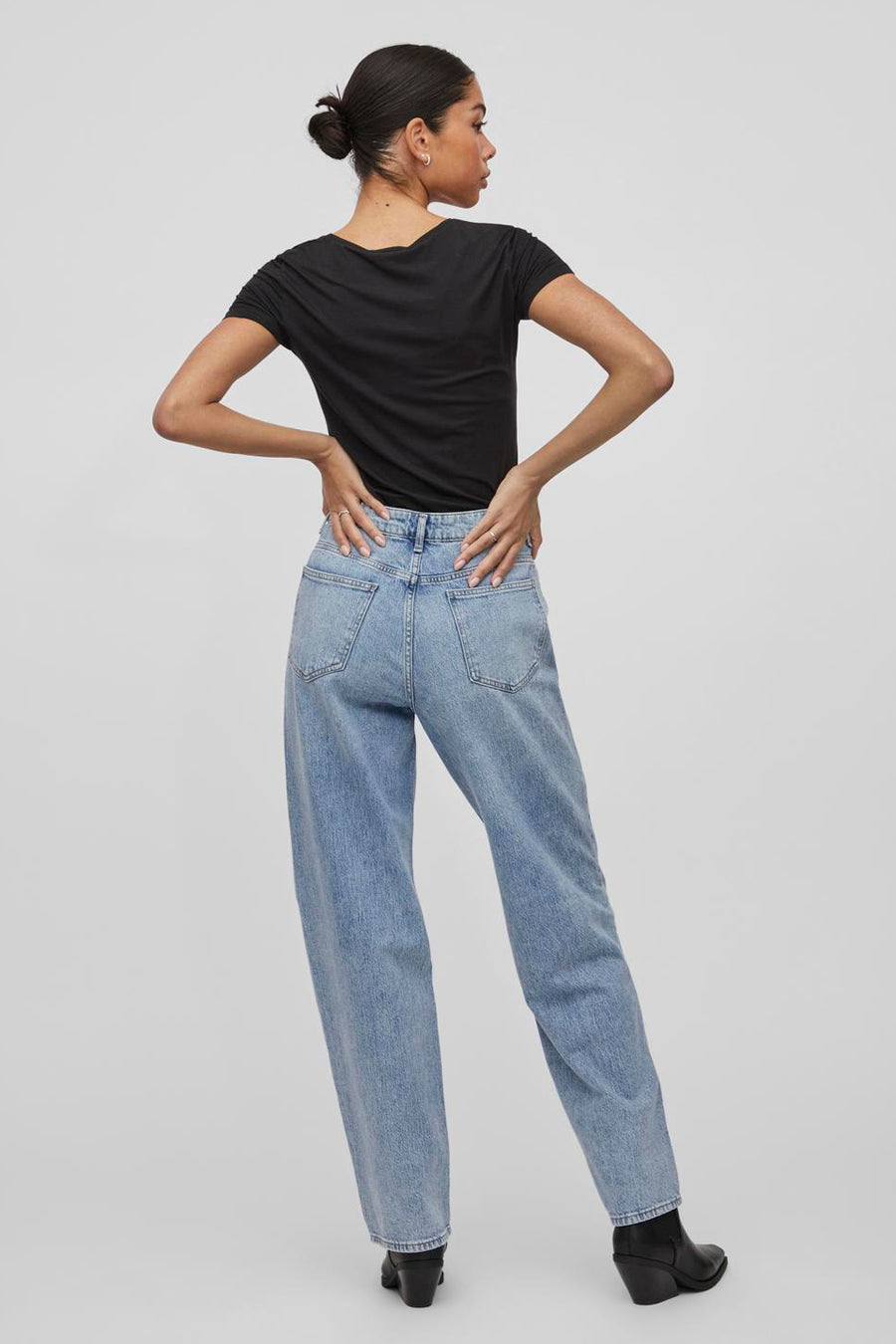 Wijde blauwe jeans van VILA, gedragen met een zwart T-shirt en zwarte leren enkellaarsjes.