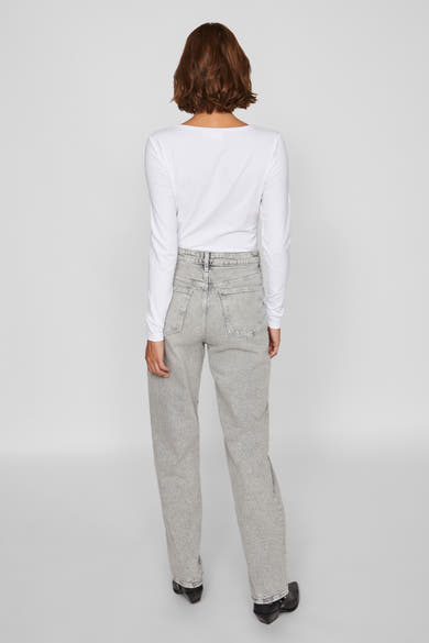 Lichtgrijze rechte jeans van VILA, gedragen met een witte top met lange mouwen en zwarte enkellaarsjes.
