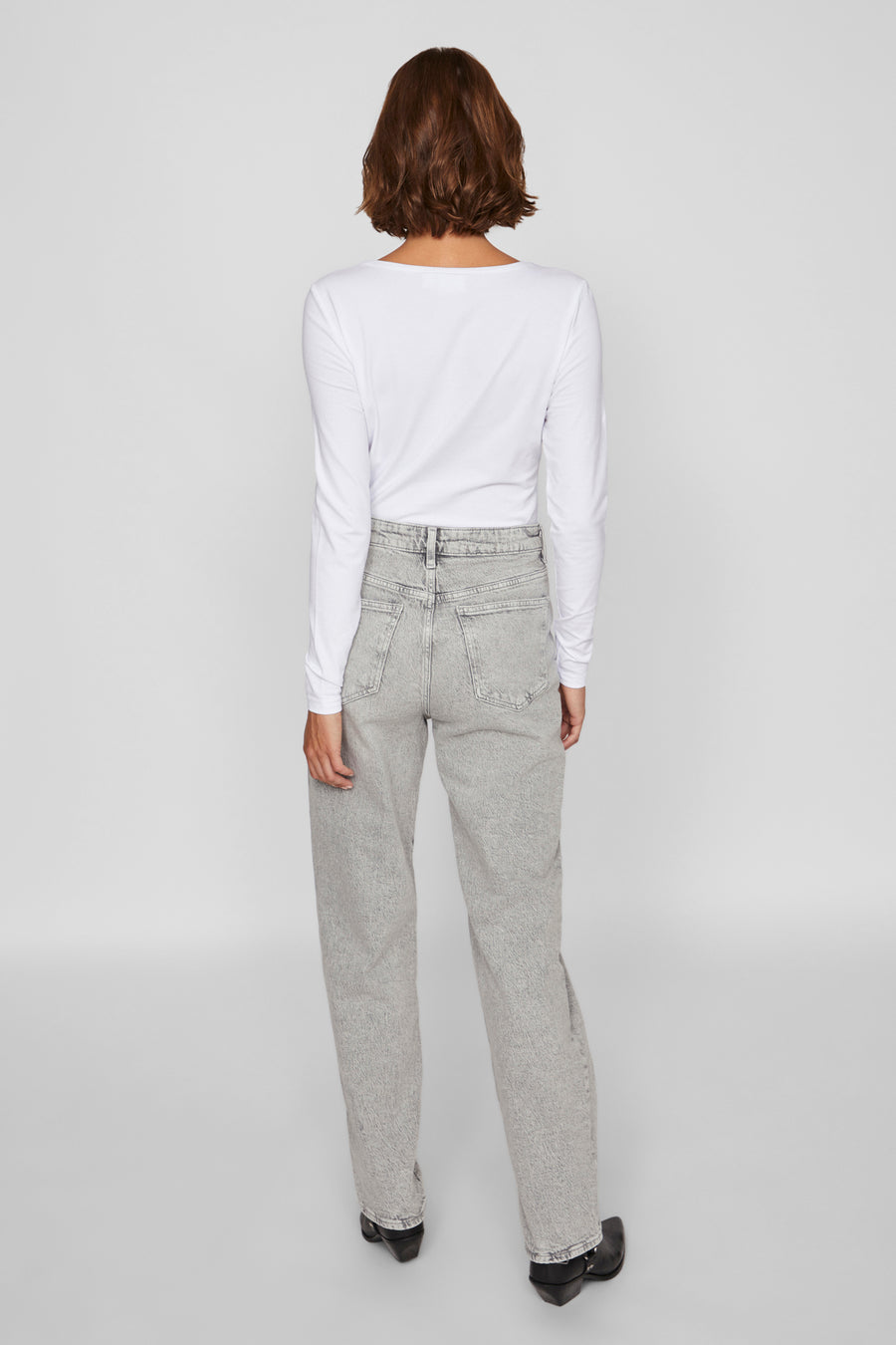 Lichtgrijze rechte jeans van VILA, gedragen met een witte top met lange mouwen en zwarte enkellaarsjes.