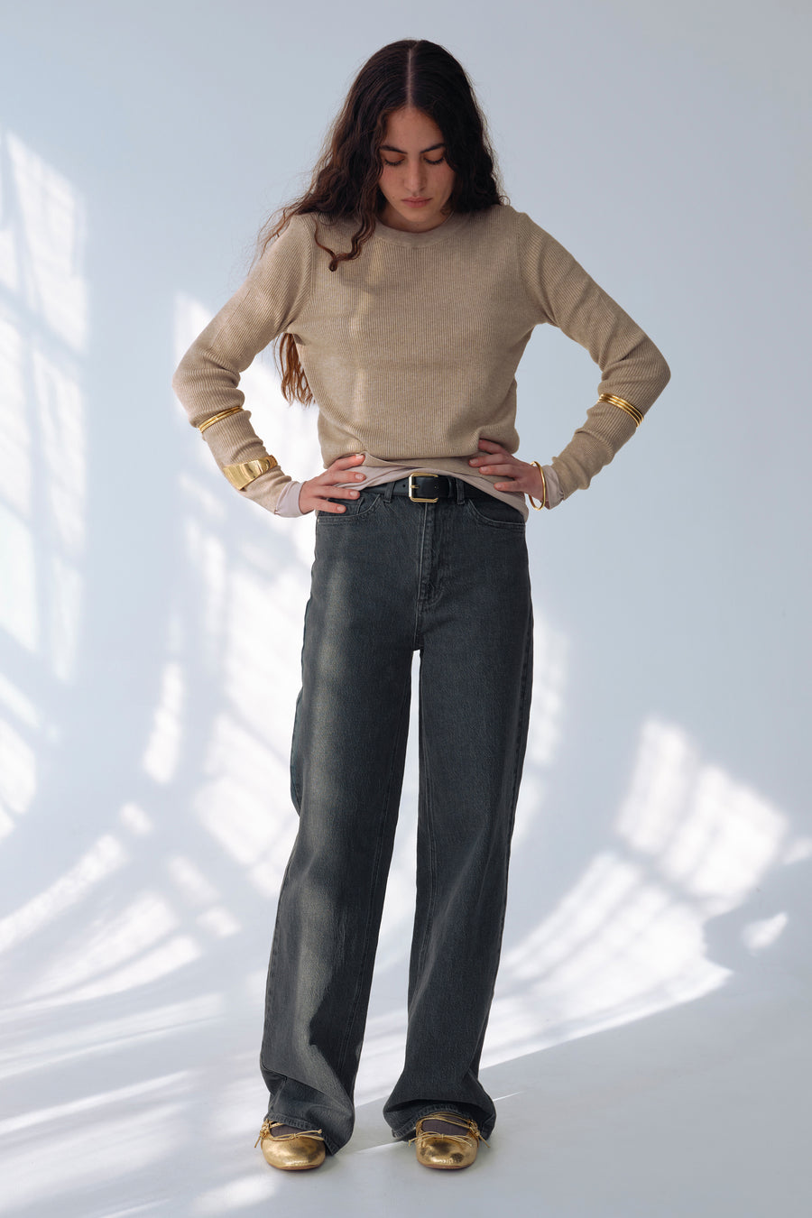 Grijze wijde jeans van VILA, gedragen met een beige trui, gouden armbanden en gouden schoenen.
