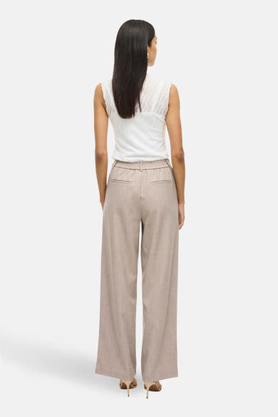 Beige broek van VILA®, met wijde pijpen en elastische taille, gedragen met een mouwloze witte top.