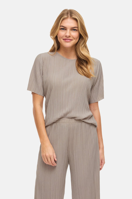 Effenchemise taupe unie à manches courtes de VILA, en tissu plissé, portée avec un pantalon assorti et des mules à talons.