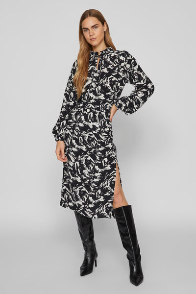 Chemisier noir à manches longues par VILA®, à motif contrastant, porté avec des bottes noires hautes.

