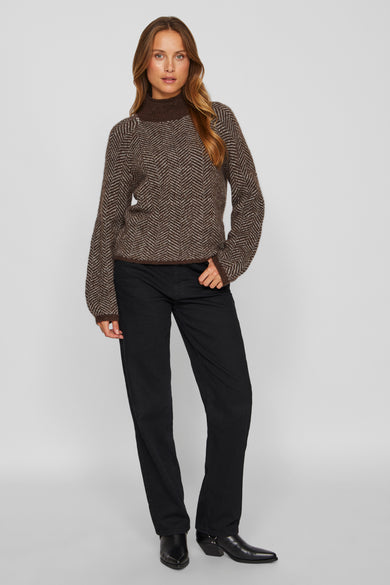 Bruine coltrui van VILA®, met chevronpatroon en gedragen met een zwarte jeans en laarzen.