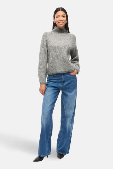 Pull à col roulé gris by VILA, avec motif chevrons et porté avec un jean ample bleu.
