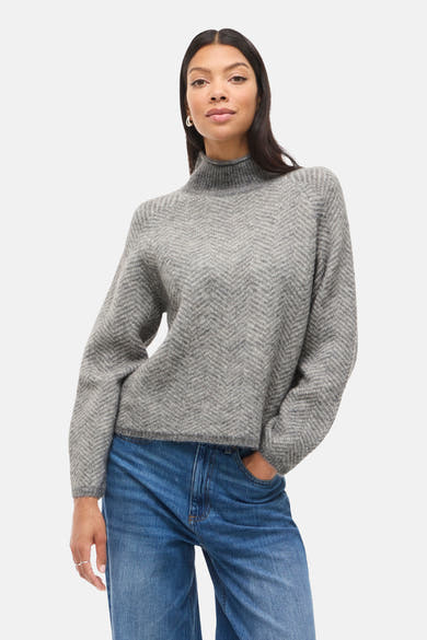 Pull à col roulé gris by VILA®, en motif à chevrons, porté avec un jean bleu.
