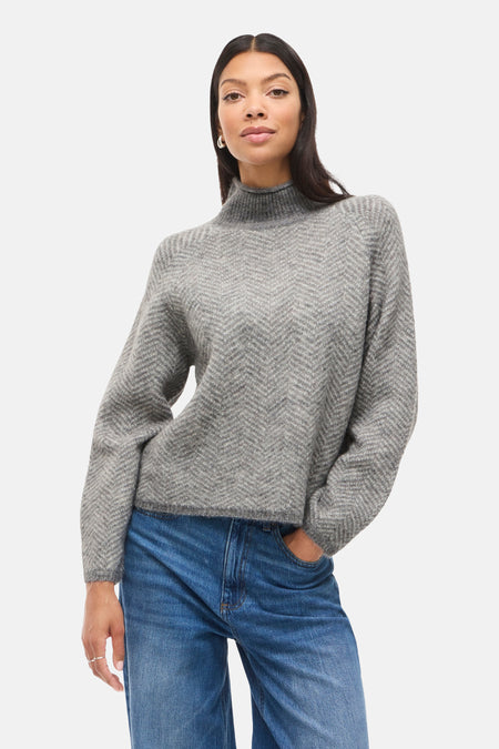 Grijze coltrui van VILA, met chevronpatroon en gedragen met een wijde blauwe jeans.