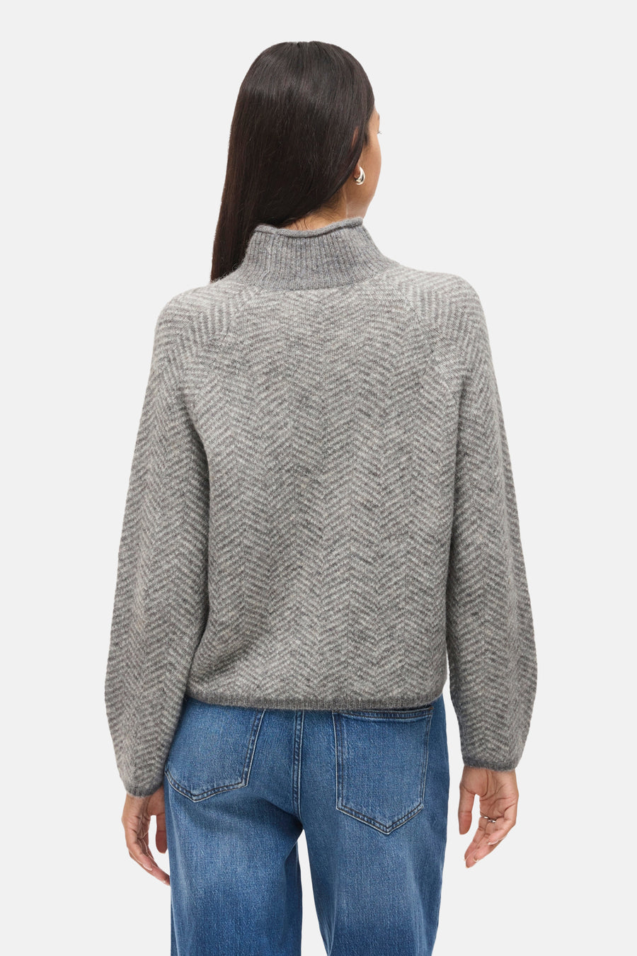 Pull à col roulé gris de VILA, avec un motif à chevrons, porté avec un jean bleu.