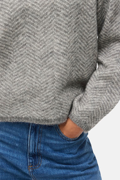 Pull col montant gris de VILA®, à motif chevrons, porté avec un jean bleu.
