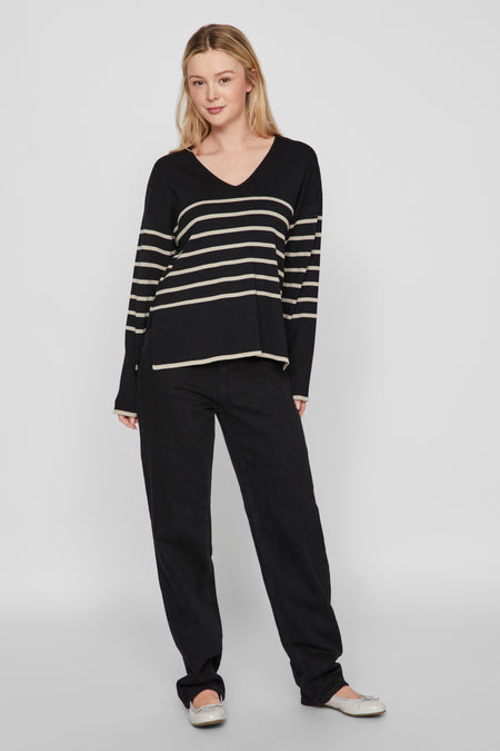 Zwarte V-hals trui van VILA®, met horizontale strepen, gedragen met een zwarte jeans en zilveren ballerina's.