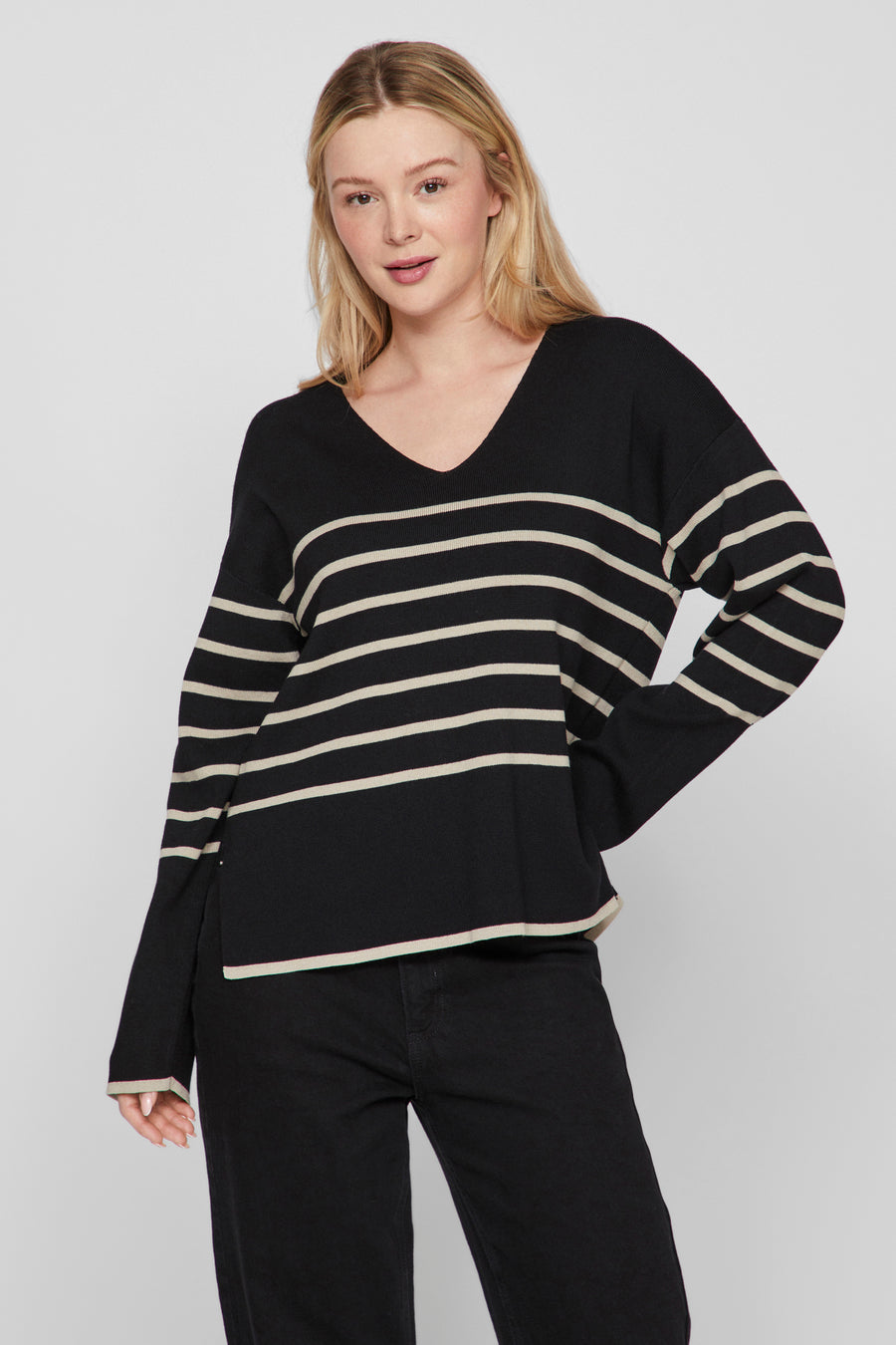 Zwarte V-hals trui van VILA® met beige horizontale strepen, gedragen met een zwarte broek.