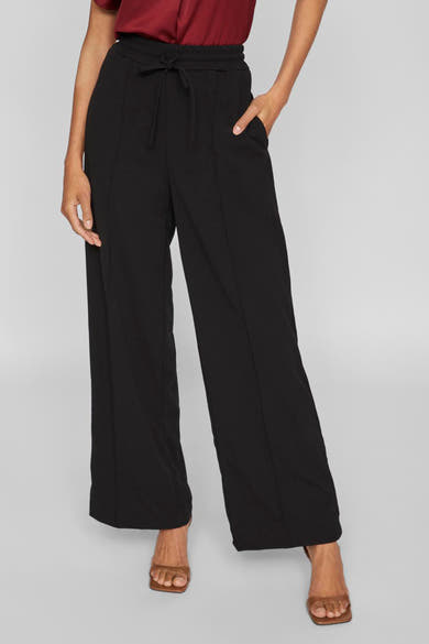 Wijde zwarte broek VILA® met elastische tailleband met trekkoord, zijzakken en een losse zoom over bruine muiltjes.