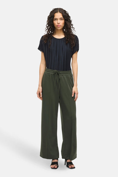 Pantalon vert de VILA, avec cordon de serrage à la taille et jambes larges, porté avec un haut plissé noir et des talons hauts noirs.
