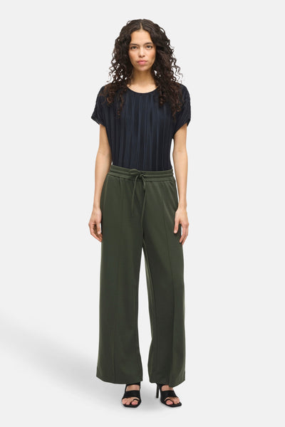 Pantalon vert de VILA, avec cordon de serrage à la taille et jambes larges, porté avec un haut plissé noir et des talons hauts noirs.
