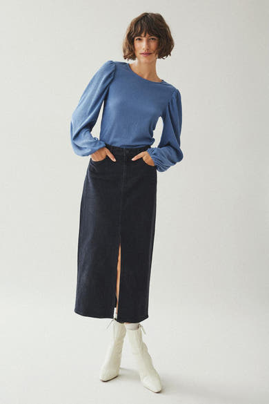 Zwarte 3/4 spijkerrok van VILA, met een split aan de voorkant en gedragen met een blauwe blouse.