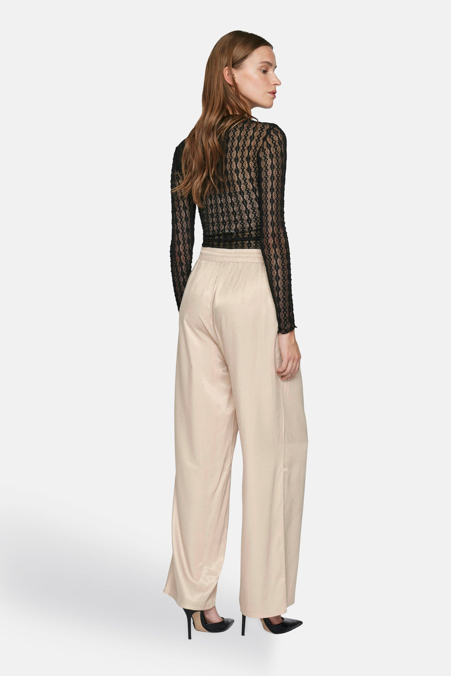 Beige broek van VILA®, wijdvallend, met een satijnen textuur, gedragen met een zwart kanten top en zwarte pumps.