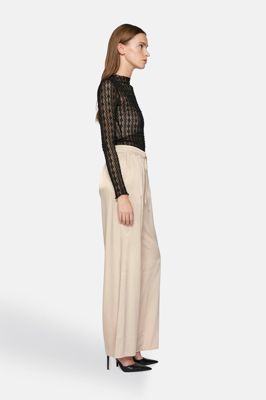 Beige broek van VILA, wijd en vloeiend, met trekkoorden in de taille en gedragen met zwarte pumps.