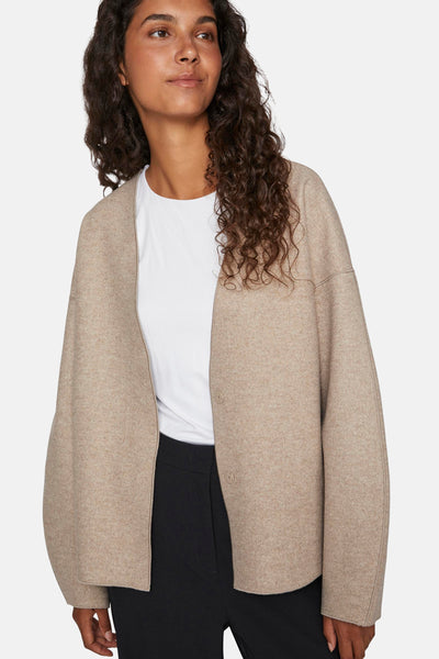Veste courte beige de VILA, portée sur un t-shirt blanc et un pantalon noir.