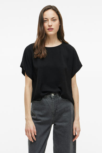 Zwart T-shirt met korte mouwen van VILA, gedragen met een lichtgrijze jeans.