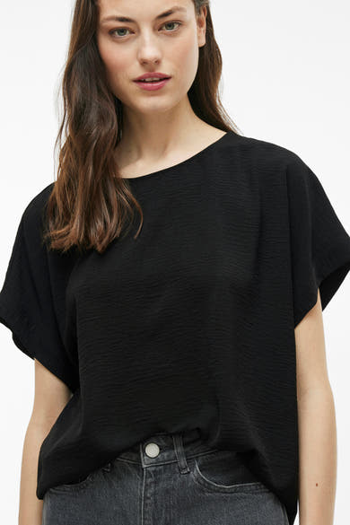 Zwart T-shirt met korte mouwen van VILA, met een licht golvende textuur, gedragen met een lichtgrijze jeans.