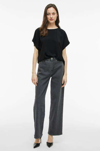 Zwart T-shirt met korte mouwen van VILA, gedragen met een lichtgrijze jeans en zwarte pumps.